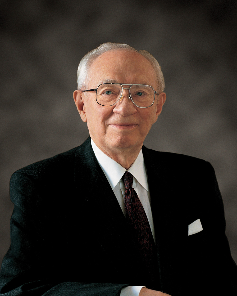 Picture of Hinckley in a black and white suit smiling at the camera